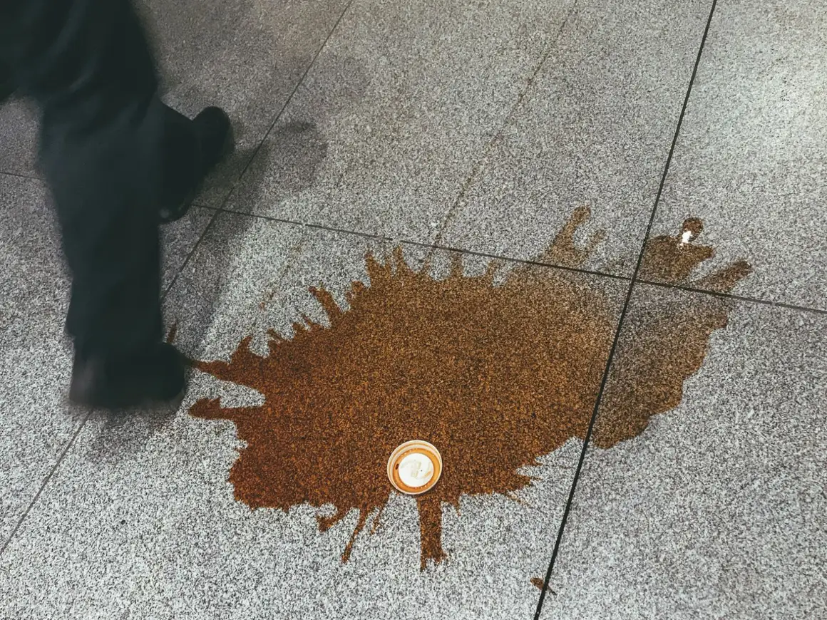 A spilled takeaway coffee on a pavement as someone walks past